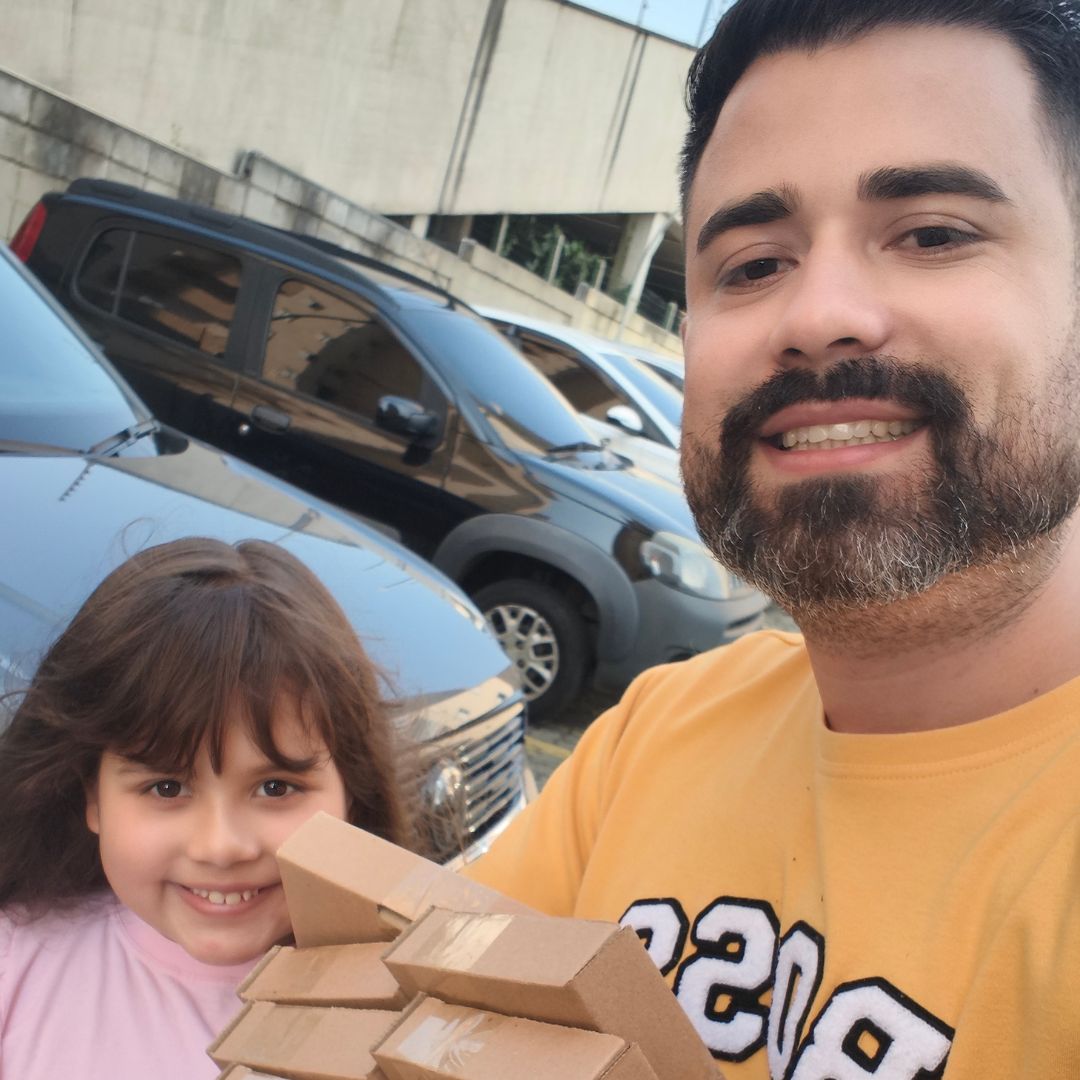 Luan e a filha segurando pedidos no estacionamento
